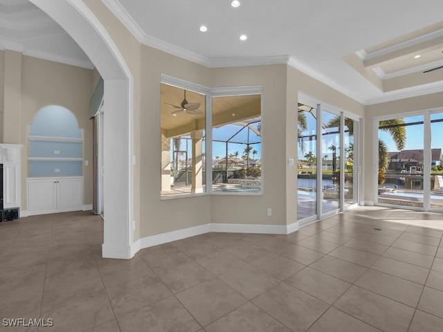 tiled empty room featuring a water view, ceiling fan, ornamental molding, and built in features