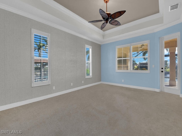 carpeted spare room with ornamental molding, ceiling fan, and a tray ceiling