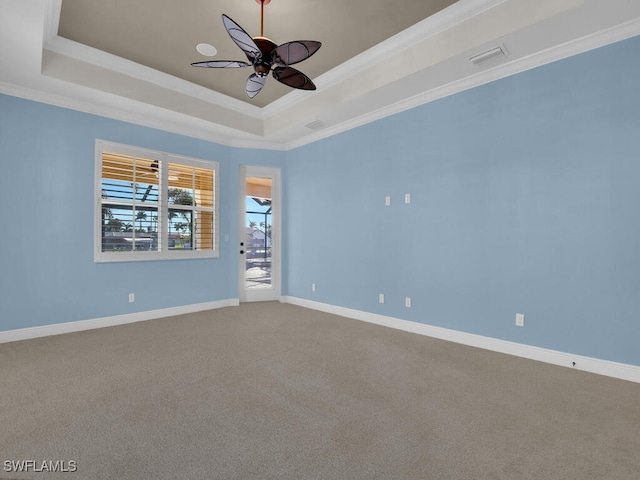 carpeted empty room with crown molding, a tray ceiling, and ceiling fan