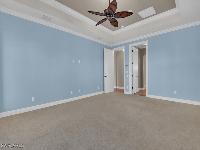 empty room with ceiling fan, ornamental molding, carpet flooring, and a raised ceiling