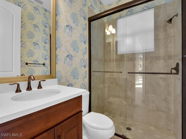 bathroom with vanity, toilet, and a shower with door