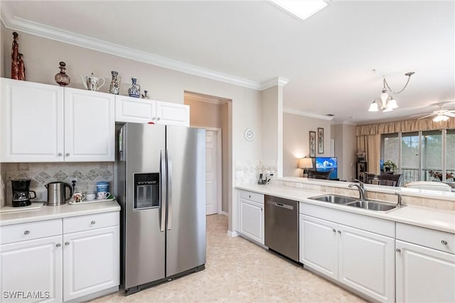 kitchen with stainless steel appliances, crown molding, ceiling fan with notable chandelier, white cabinets, and sink