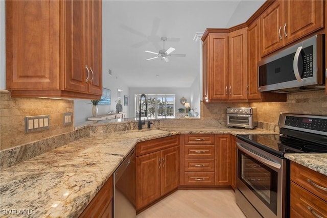 kitchen with light stone counters, ceiling fan, stainless steel appliances, and sink