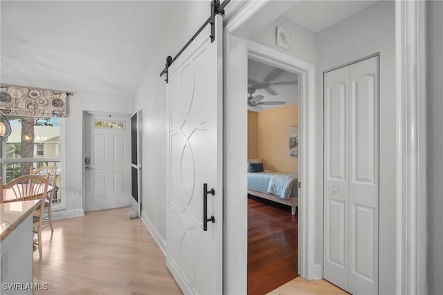 hall with a barn door and light wood-type flooring