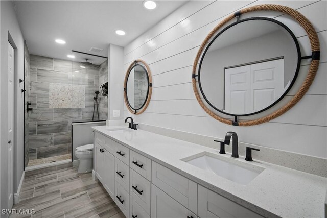 bathroom with vanity, tiled shower, and toilet