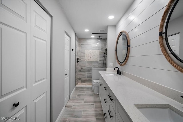 bathroom with vanity, tiled shower, and toilet