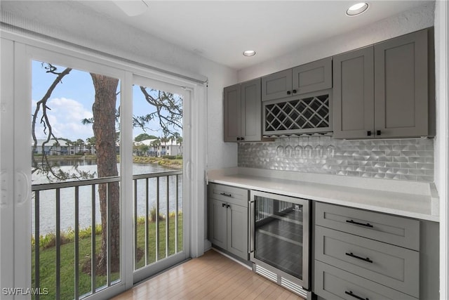 bar with a water view, beverage cooler, and gray cabinets