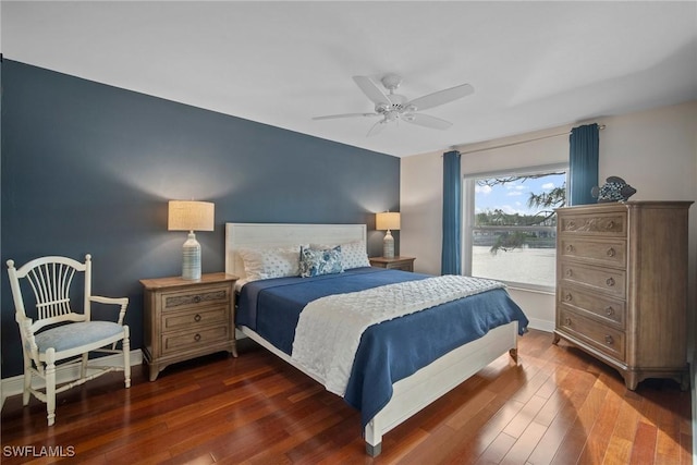 bedroom with ceiling fan, a water view, and dark hardwood / wood-style flooring