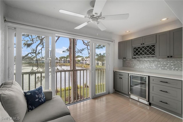 bar featuring wine cooler, a water view, and gray cabinetry