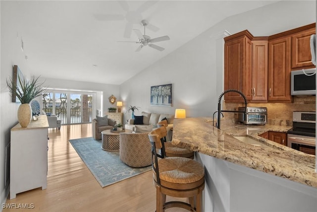 living room with ceiling fan, lofted ceiling, light hardwood / wood-style floors, and sink