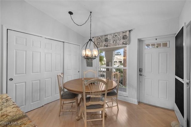 dining space with light hardwood / wood-style flooring, vaulted ceiling, and a chandelier