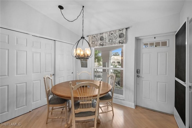 dining room featuring an inviting chandelier, vaulted ceiling, and light wood-type flooring