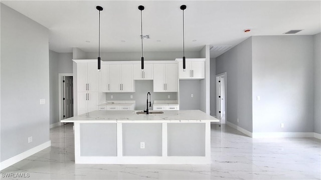 kitchen featuring a large island with sink, white cabinets, and decorative light fixtures