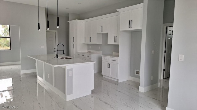 kitchen featuring pendant lighting, sink, white cabinetry, and a kitchen island with sink