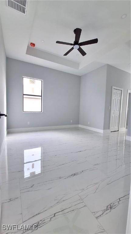 unfurnished room featuring ceiling fan and a tray ceiling