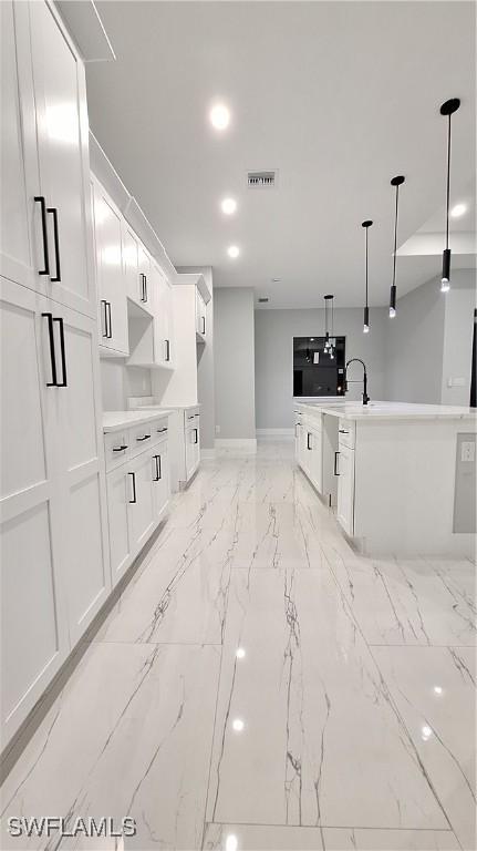 kitchen with recessed lighting, white cabinetry, marble finish floor, light countertops, and hanging light fixtures