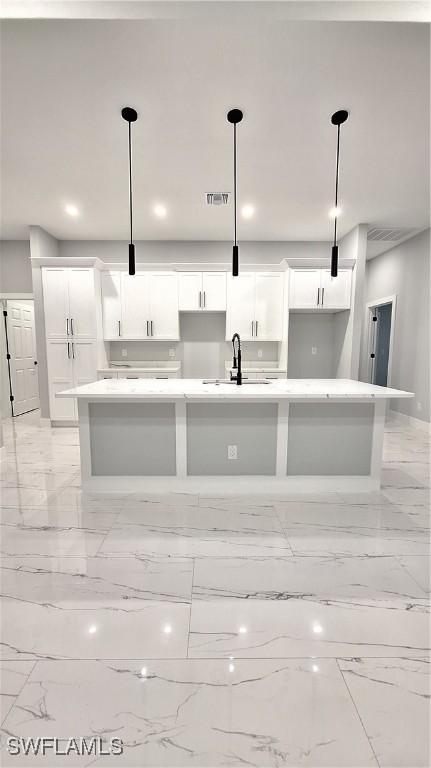 kitchen featuring a spacious island, a sink, and decorative light fixtures