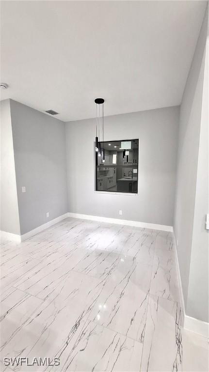 spare room with marble finish floor, baseboards, and visible vents