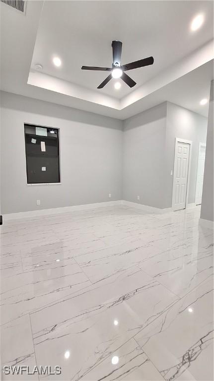 unfurnished room featuring ceiling fan, visible vents, baseboards, marble finish floor, and a raised ceiling