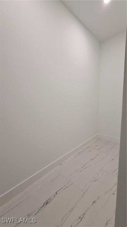 unfurnished room featuring marble finish floor and baseboards