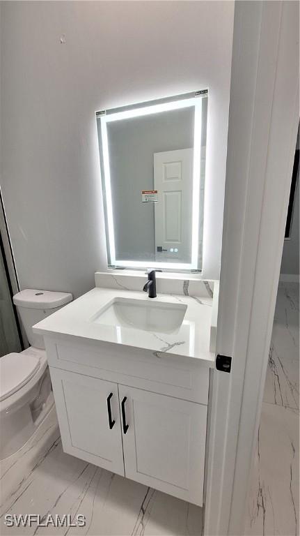 full bath featuring marble finish floor, vanity, and toilet