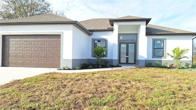 prairie-style house with a front lawn, driveway, an attached garage, and stucco siding