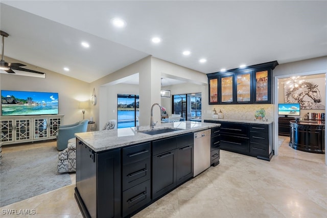 kitchen featuring sink, light stone counters, vaulted ceiling, dishwasher, and an island with sink