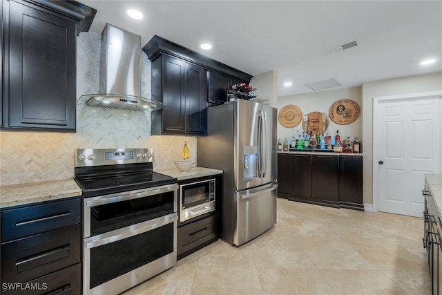 kitchen with light stone counters, decorative backsplash, stainless steel appliances, and wall chimney exhaust hood