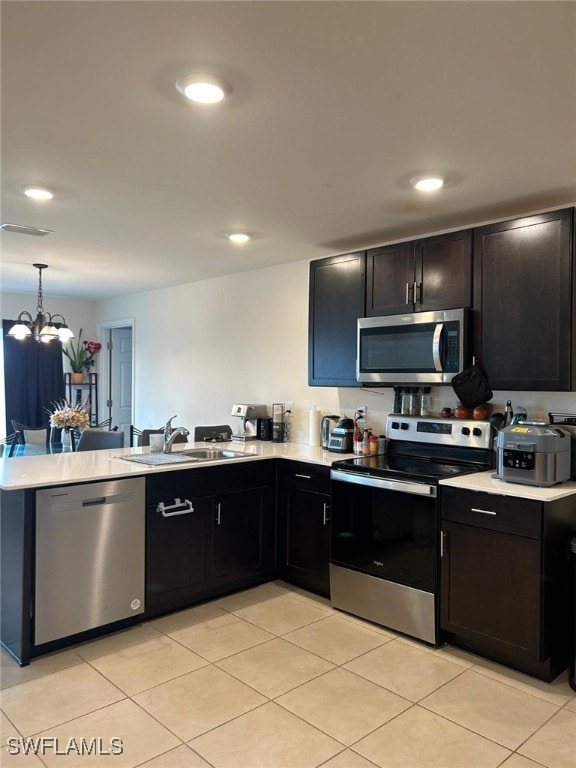 kitchen featuring a notable chandelier, kitchen peninsula, sink, appliances with stainless steel finishes, and light tile patterned floors