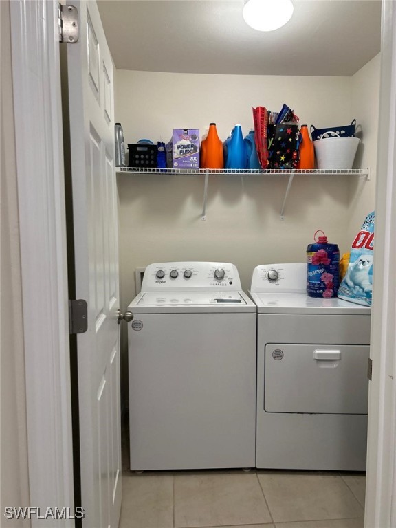 clothes washing area with light tile patterned flooring and washing machine and clothes dryer