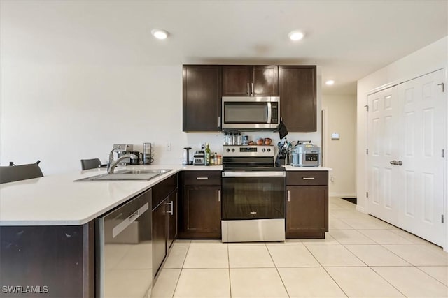 kitchen featuring stainless steel appliances, kitchen peninsula, sink, and light tile patterned floors