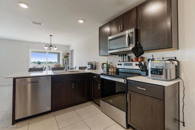 kitchen featuring light tile patterned flooring, sink, hanging light fixtures, kitchen peninsula, and stainless steel appliances