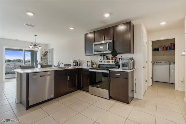 kitchen with sink, appliances with stainless steel finishes, hanging light fixtures, independent washer and dryer, and kitchen peninsula