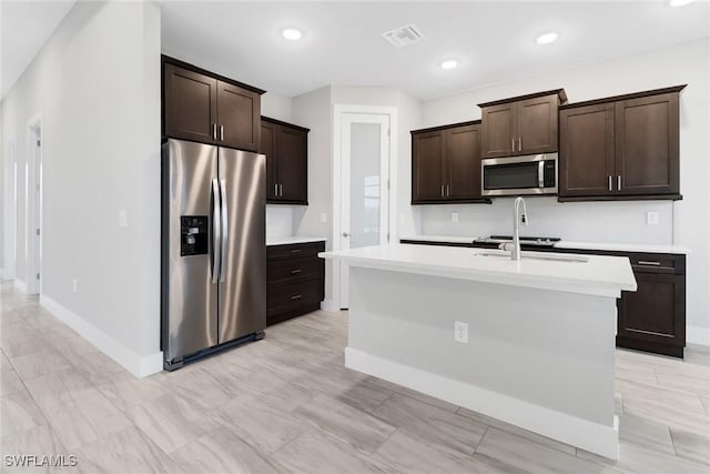 kitchen with sink, dark brown cabinetry, stainless steel appliances, and a kitchen island with sink