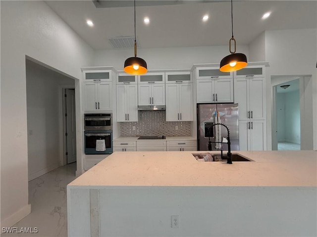 kitchen with stainless steel appliances, tasteful backsplash, pendant lighting, white cabinets, and sink