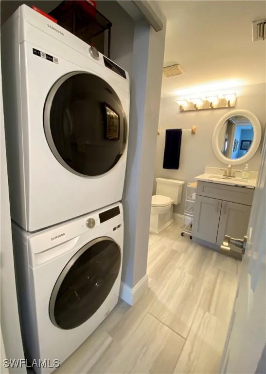 laundry area with stacked washer and clothes dryer and sink