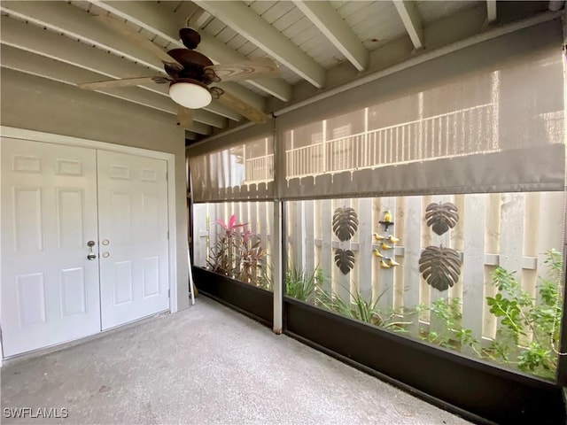 unfurnished sunroom featuring beamed ceiling and ceiling fan