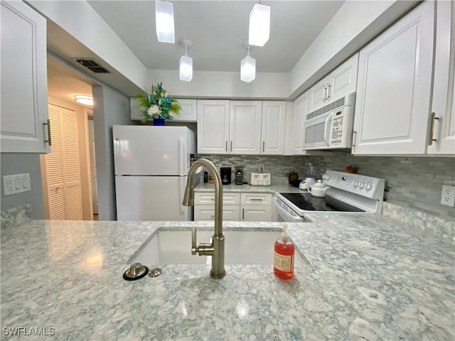 kitchen featuring backsplash, white cabinets, hanging light fixtures, light stone counters, and white appliances