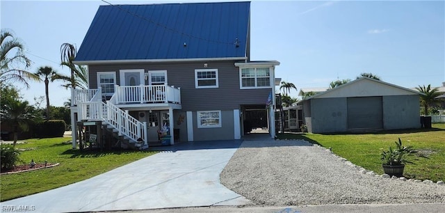 coastal home with a front yard, metal roof, driveway, and stairway