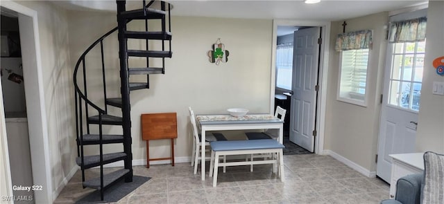 tiled dining space featuring stairway and baseboards