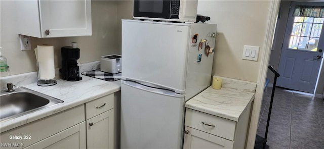 kitchen featuring white refrigerator, white cabinetry, and dark tile patterned flooring