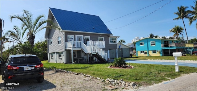 raised beach house featuring metal roof, a front lawn, and stairs