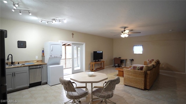 dining area with a healthy amount of sunlight, baseboards, stacked washer / drying machine, and ceiling fan