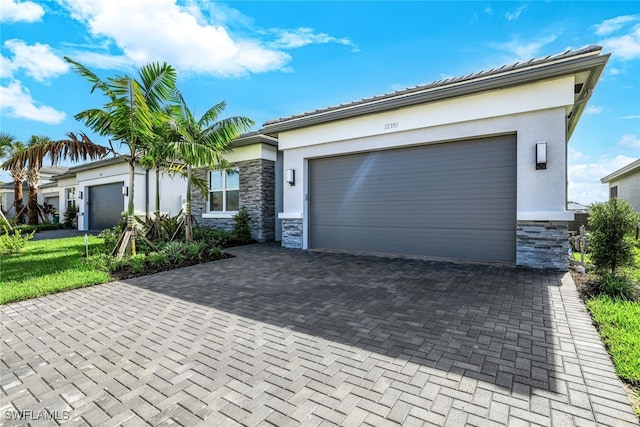 12390 Purple Ficus Way, Naples, FL 34120 - view of front of home with stone siding, stucco siding, decorative driveway, and a garage