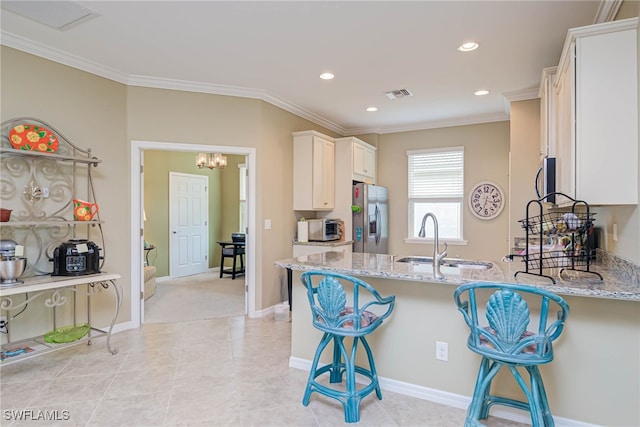 kitchen with light stone countertops, a breakfast bar, stainless steel fridge with ice dispenser, and sink