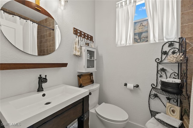 bathroom with walk in shower, vanity, and toilet