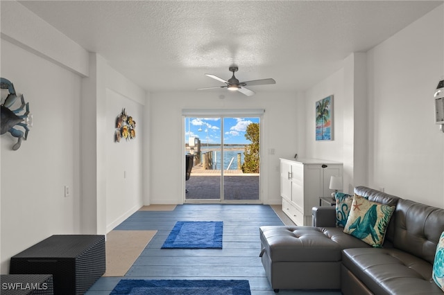 living room with ceiling fan, a textured ceiling, and light wood-type flooring