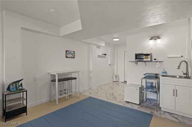 interior space with white cabinetry, sink, and a textured ceiling