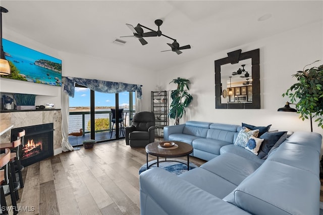 living room with ceiling fan, wood-type flooring, and a premium fireplace