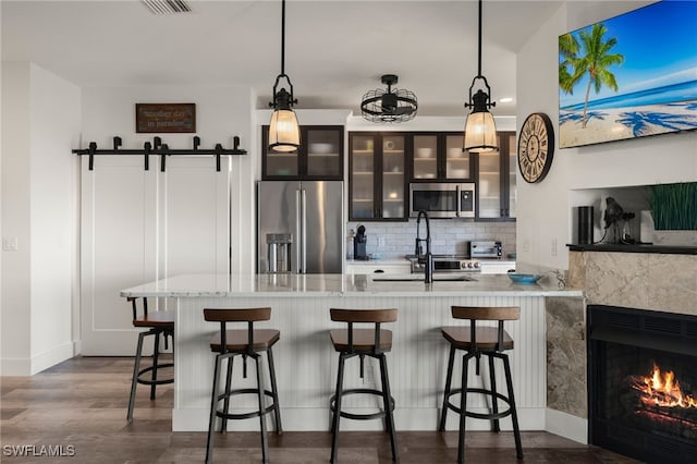 kitchen featuring pendant lighting, a kitchen bar, a barn door, and appliances with stainless steel finishes